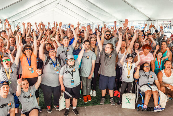 2021 ABLE Games athletes and volunteers pose for a group photo under a tent.